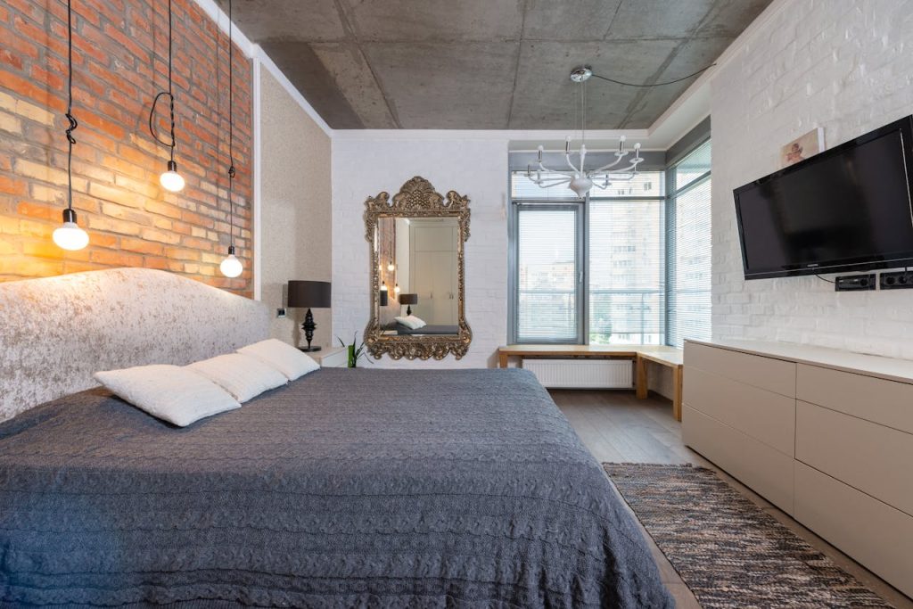 Contemporary bedroom with king size bed, large mirror, and mounted television.